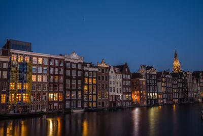 Illuminated buildings against sky at dusk