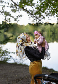 Happy mother carrying baby daughter