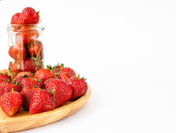 Close-up of strawberries in jar against white background