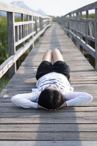 Rear view of woman lying down on footpath