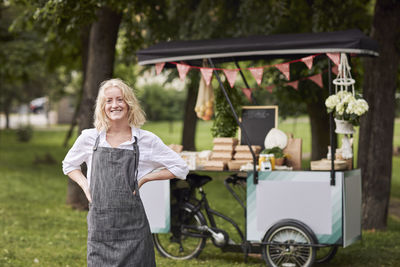 Smiling woman looking at camera, food stall on background