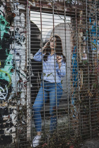 Portrait of young woman seen through metal grate