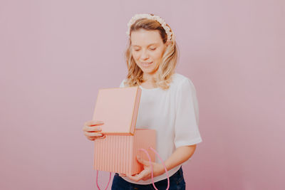 Woman holding book against gray background