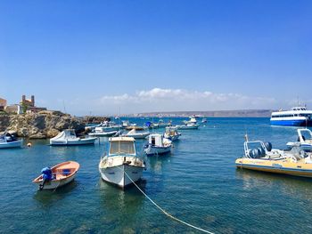 Boats moored in sea against blue sky