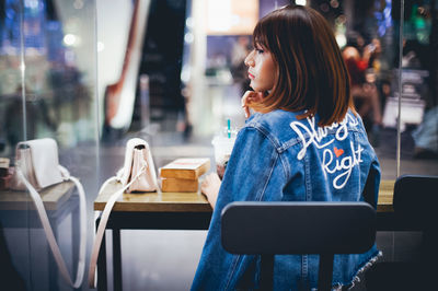 Side view of young woman using mobile phone at night