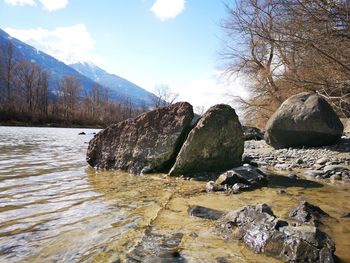 Rocks by river against sky