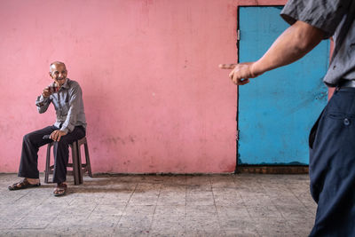 Man holding umbrella against wall in city