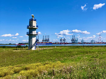 Lighthouse on field against sky