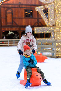 Cute sibling playing on snow covered land