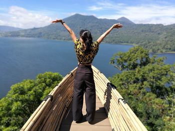 Rear view of woman with arms raised standing in observation point