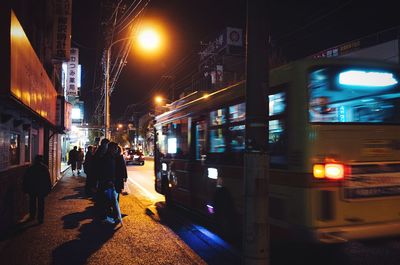 People at illuminated railroad station in city at night