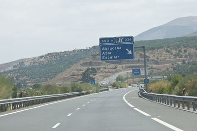 Road sign by mountains against sky