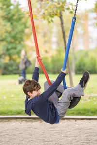 Kid play hanging from steel colourful ropes in a park.