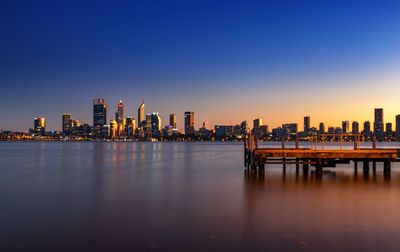 Illuminated buildings in city against sky during sunset