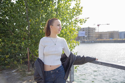 Portrait of young woman standing against trees