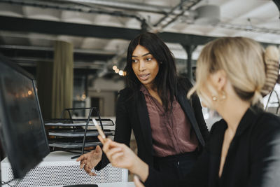 Female entrepreneurs discussing over desktop pc at office