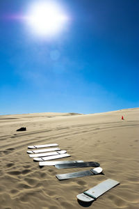 Sandboards at desert against clear sky on sunny day