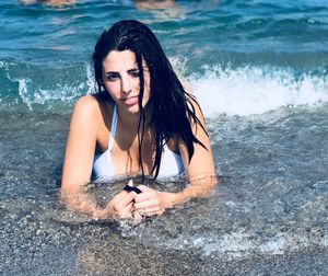 Portrait of beautiful young woman lying at beach