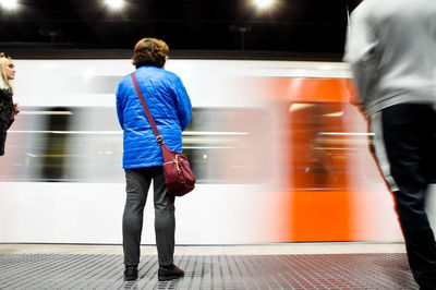Rear view of man standing on train at railroad station platform