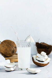 Coconut milk in a glass and pieces of tropical fruit on the table. natural source of antioxidants