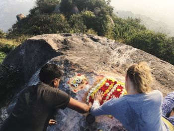 Rear view of people standing by tree against mountain