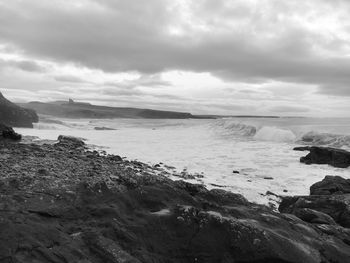 View of calm beach against cloudy sky