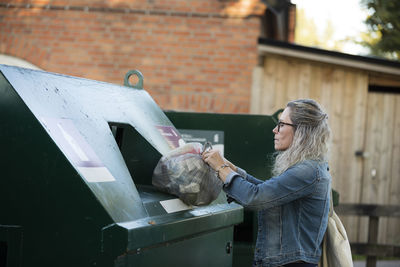 Blond woman throwing rubbish into waste bin