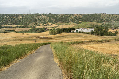 Road amidst field against sky