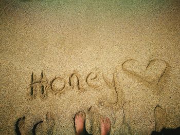 Low section of person standing by honey text at beach