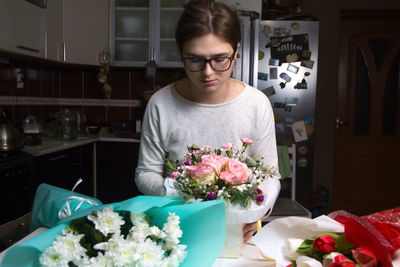 A female florist works on a beautiful bouquet at night in her flower shop. this scene captures 
