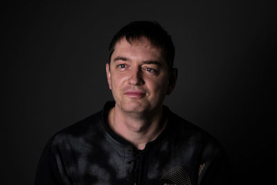 Portrait of young man against black background