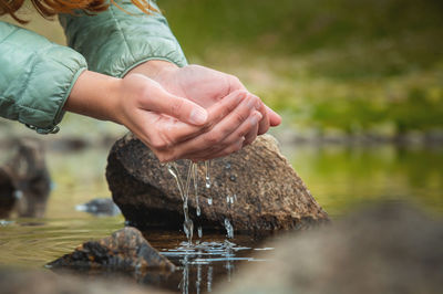 Close-up of a woman's hand pouring water from her palms while trying to drink from a clean water