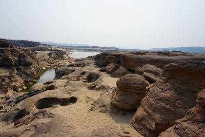 Rock formations on beach against clear sky