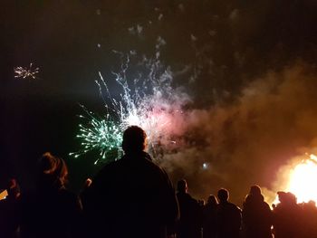 Rear view of silhouette people watching firework display at night
