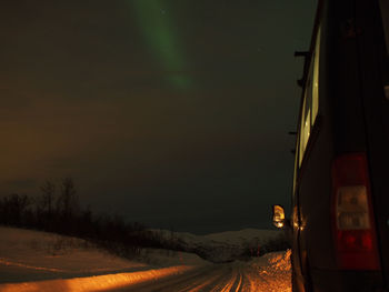 Car on snow covered field against sky at night