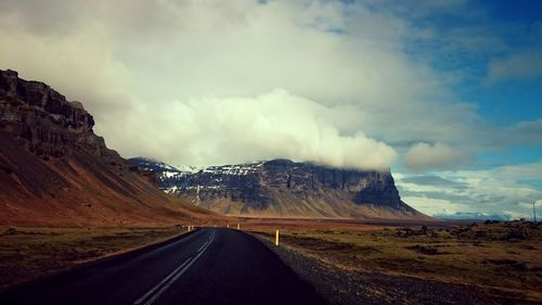 Road leading towards mountains against sky