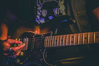 Midsection of man playing guitar at music concert