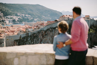 Rear view of man and woman standing on mountain in city