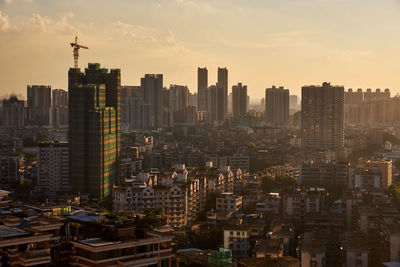 Aerial view of buildings in city against sky during sunset