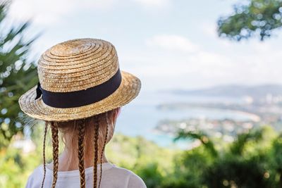 Rear view of girl in hat against sky