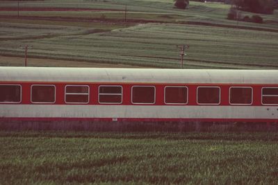 Red train amidst grassy field