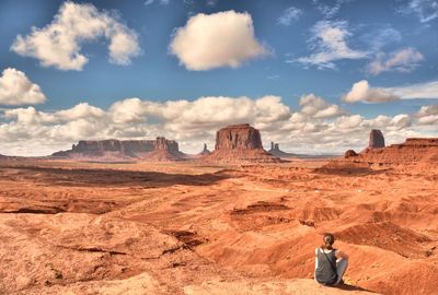 Man standing on rock formations in desert against sky