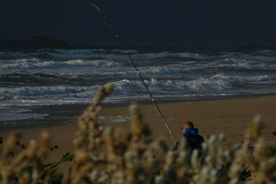 People fishing in sea against sky