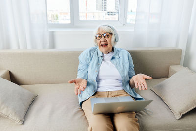 Young woman using laptop while sitting on sofa at home