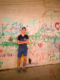 Portrait of man standing against graffiti wall