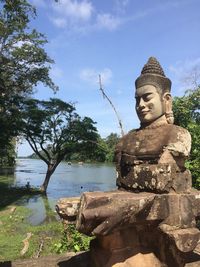 Statue of buddha sitting against trees