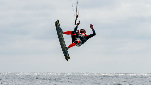 Low angle view of man kiteboarding in sea against sky