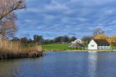 Houses by lake against sky