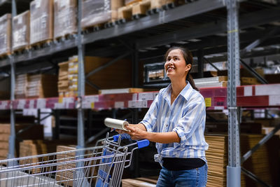 Smiling entrepreneur writing while standing in warehouse