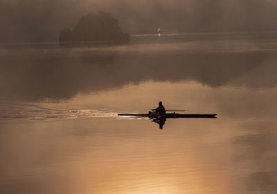 Silhouette in woman on boat in lake during sunset